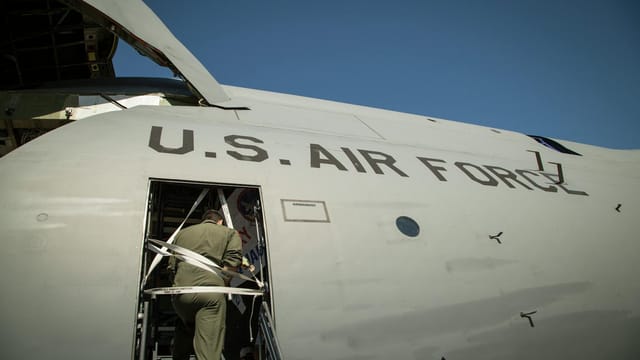 US Air Force personnel loading cargo into a military transport aircraft.