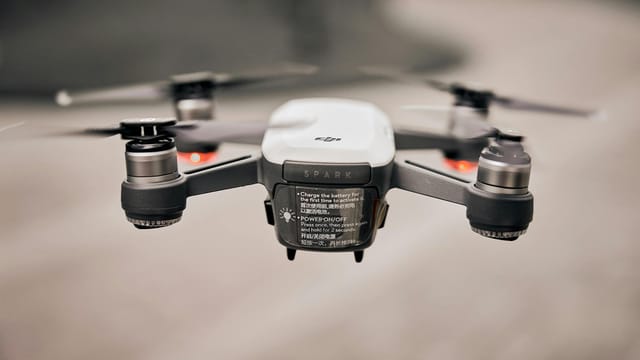 Close-up of a modern drone flying outdoors, showcasing advanced technology and propellers.
