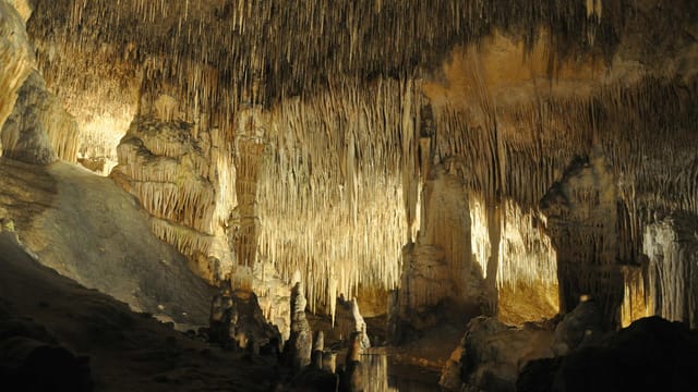 Explore stunning stalactite formations in a Mallorca cave, a geological marvel.