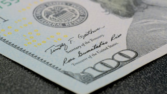 High-resolution close-up of a hundred dollar bill showing intricate security features.