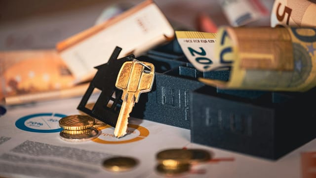 Close-up of house keys, euro bills, and charts symbolizing real estate investment and finance.