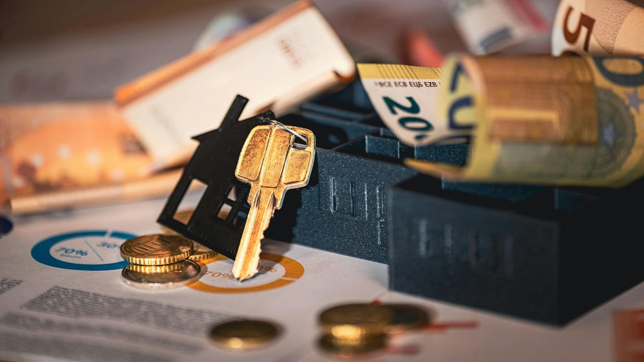 Close-up of house keys, euro bills, and charts symbolizing real estate investment and finance.