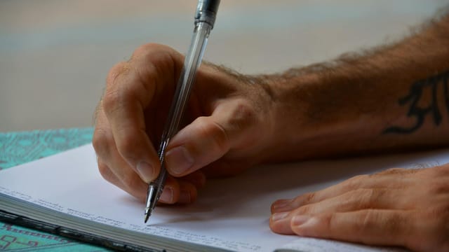 Close-up of a person writing in a notebook, focusing on hands and pen, ideal for study or business themes.