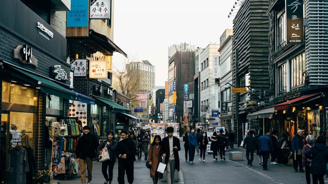 Lively shopping street in Seoul with people walking, shops, and vibrant city life.