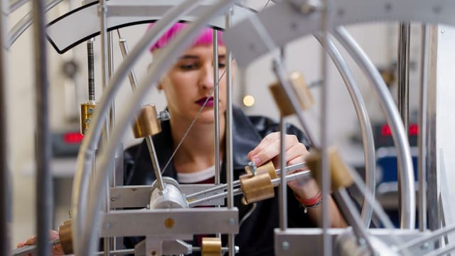 Illustrative image: A focused young female scientist adjusts equipment in a lab setting.
