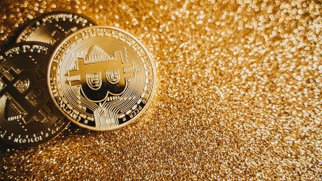 Close-up of bitcoins on a shimmering gold background, symbolizing digital wealth and investment.