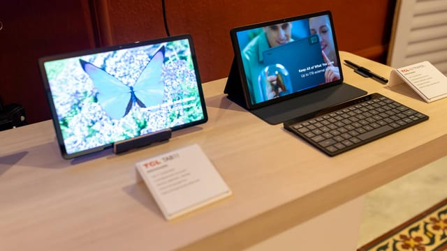 Two sleek tablets showcased with a keyboard in a technology showroom, highlighting wireless connectivity.