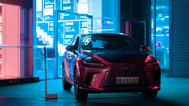 Stylish Lexus SUV parked at night, showcasing luxury in an urban landscape with vibrant neon lights.