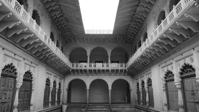 Black and white image of a historical courtyard in India, showcasing intricate architecture.
