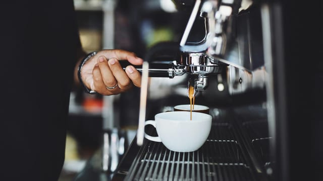 Close-up of a barista preparing espresso in a café using a machine