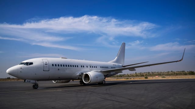 A large white commercial airplane on the runway under a clear blue sky, ready for departure.