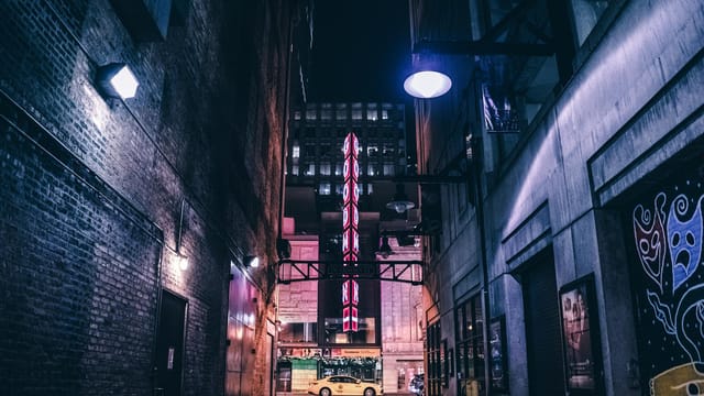 Discover the evocative mood of a Chicago alley at night with vibrant theater signage and soft lighting.