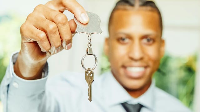 A cheerful real estate agent presents a key, symbolizing a new home purchase.