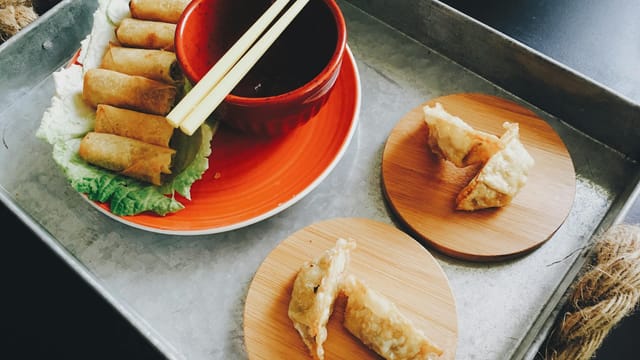 Appetizing Asian dumplings on bamboo plates with chopsticks and soy dipping sauce.