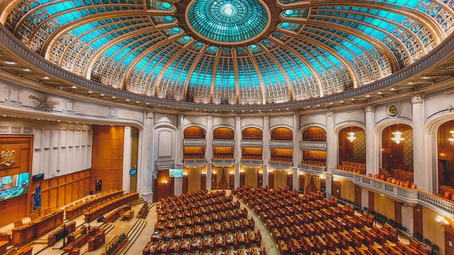 Vibrant interior of a parliament hall with a grand dome and intricate architecture.