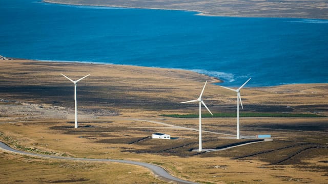 Aerial view of wind turbines on East Falkland near the ocean, showcasing sustainable energy in a natural landscape.