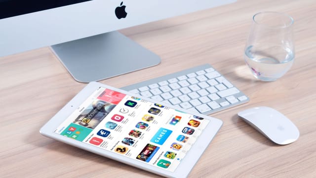 Sleek home office setup featuring an iMac and iPad showcasing apps.