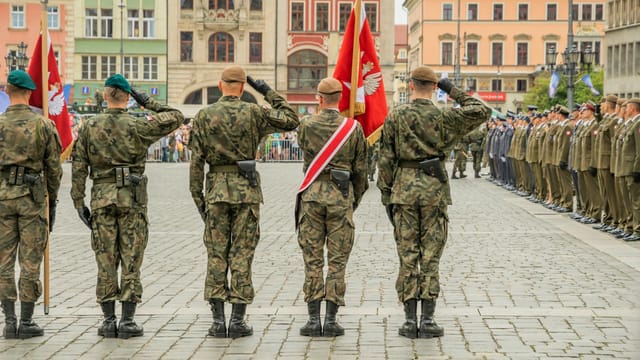 Polish soldiers saluting during a military parade in Wrocław city square, showcasing national pride.