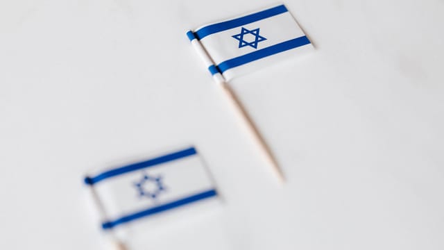 From above of small flags of Israel on toothpicks placed on white surface