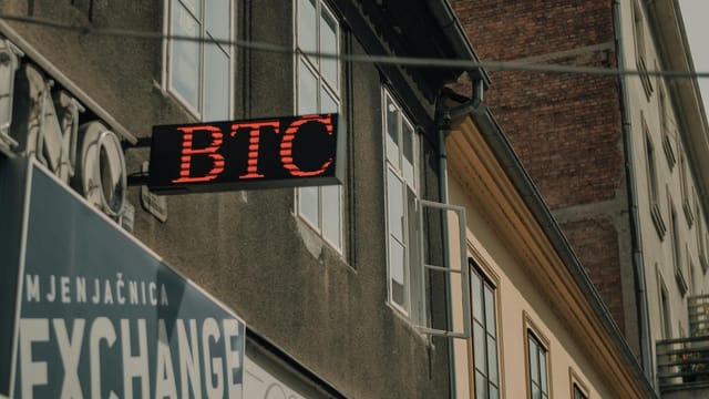 Exterior of a building featuring a prominent BTC and exchange sign, indicating a cryptocurrency location.