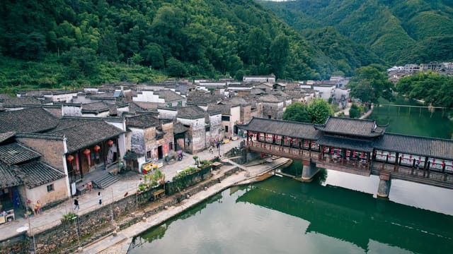 A scenic aerial shot capturing a traditional village and river in Jiangxi, China. Ideal for travel and culture themes.