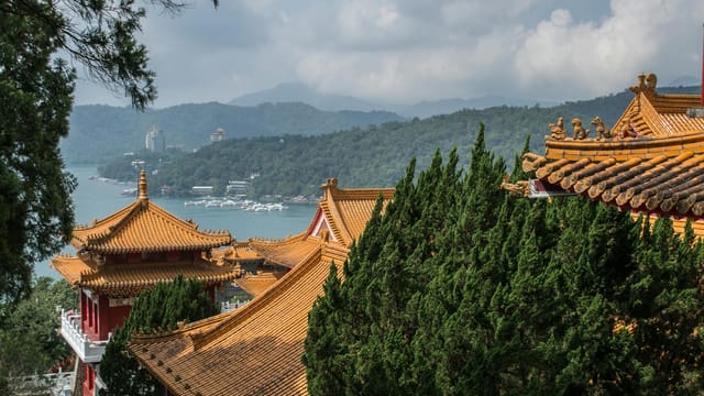 Golden-roofed Wen Wu Temple amidst lush green trees with Sun Moon Lake in the background.