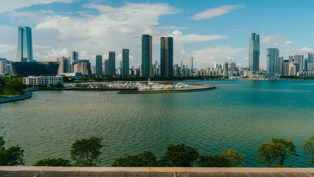 Panoramic view of a city skyline with modern skyscrapers along a picturesque waterfront.