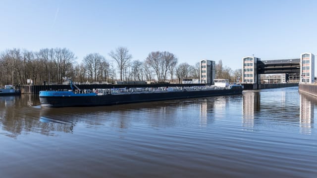 A cargo ship navigates through the Geesthacht floodgate on a clear day in Schleswig-Holstein, Germany.