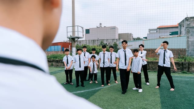 A group of young students in uniform standing outdoors on a sports field.