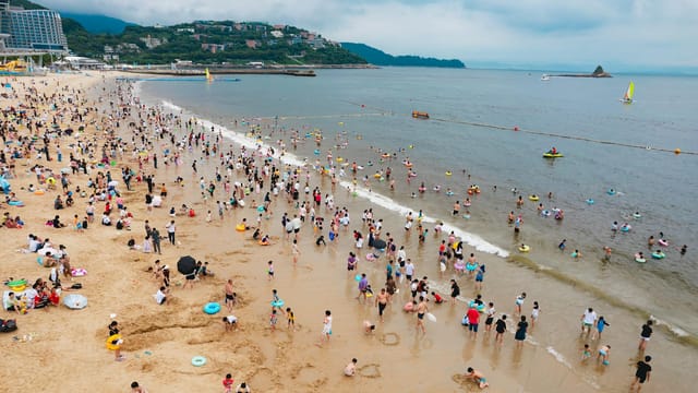 A lively summer scene at the beach in Shen Zhen Shi with crowds enjoying the seaside.