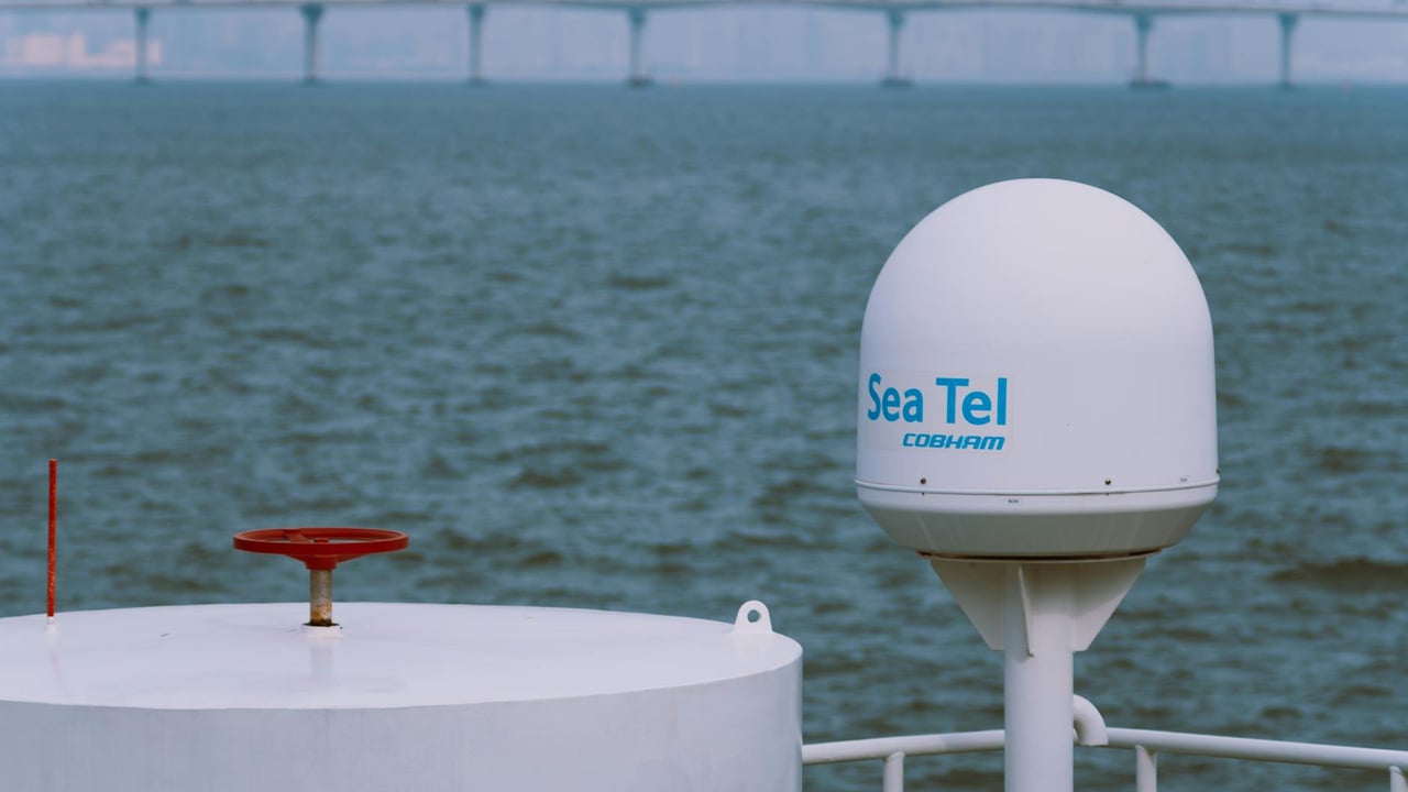 A Sea Tel satellite antenna on a vessel with a bridge in the background over the ocean.