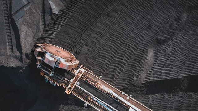 From above of industrial machine with conveyor belts digging and transporting coal in daylight