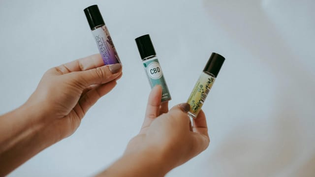 Close-up of hands holding CBD and essential oil bottles, featuring lavender, showcasing natural wellness products.