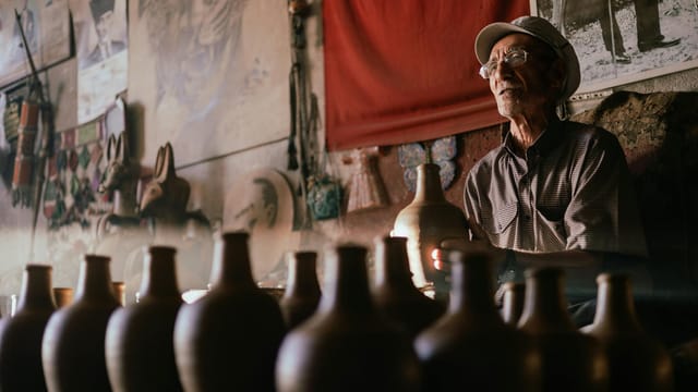 An artisan potter skillfully shaping earthen pots in a dimly lit Avanos workshop.