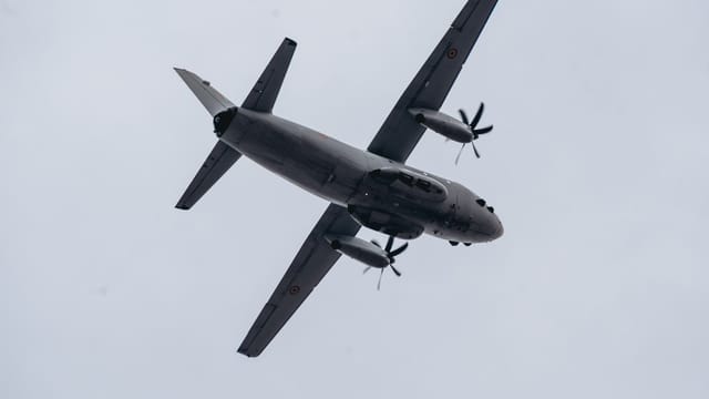 Low angle shot of a military aircraft flying against a gray sky in Bucharest, Romania.