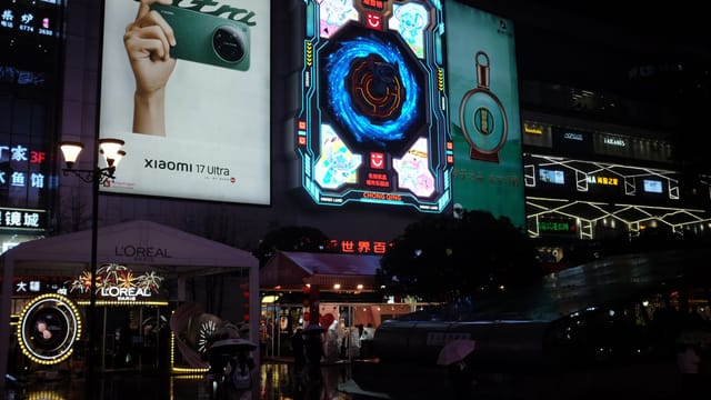 Vibrant urban cityscape at night showcasing illuminated neon billboards and bustling street life.