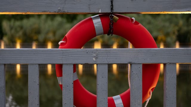 Red lifebuoy on a pier fence in Shanghai, captured at sunset, with calm waters in the background.