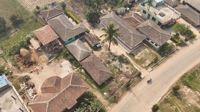 Aerial view showcasing traditional rural houses and a road in a Nepali village.