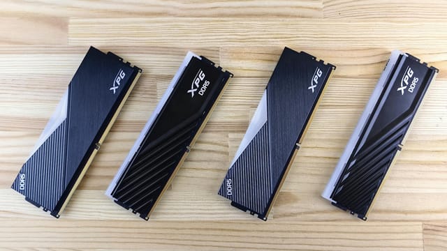 Four XPG DDR5 RAM modules aligned on a wooden surface, showcasing modern computing technology.