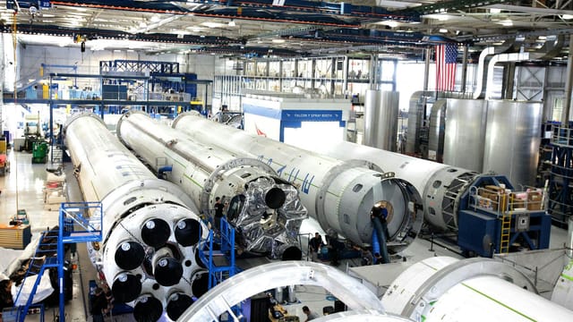 View of a spacecraft assembly line with rockets in a spacious hangar.