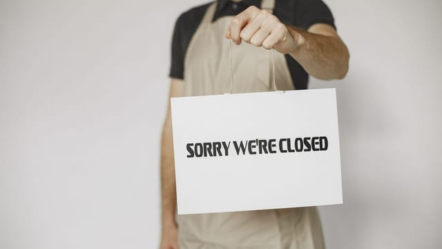 Close-up of a man holding a 'Sorry We're Closed' sign, ideal for business or retail concepts.