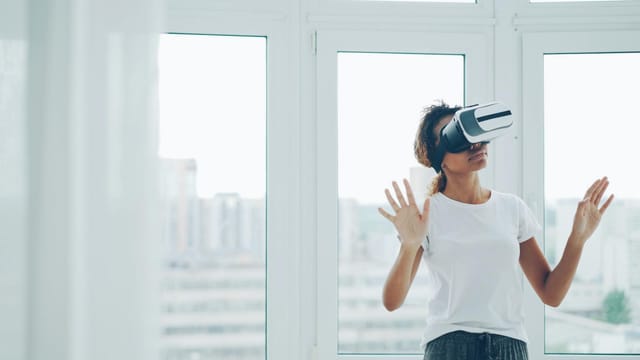 A woman enjoying a virtual reality experience with VR headset indoors.