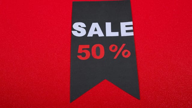 Modern sale tag offering 50% discount on vibrant red background.