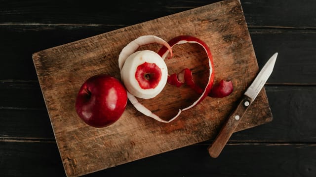 Top view of apples on a wooden board with peel and knife, perfect for food styling themes.