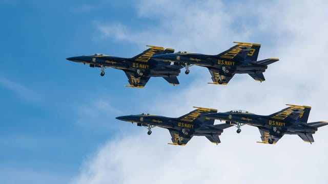 Impressive US Navy Blue Angels jets perform synchronized flight in clear blue sky.
