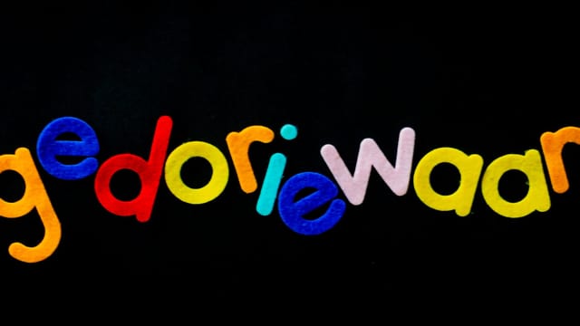 Bright multicolored felt letters spelling a creative word on a black background.