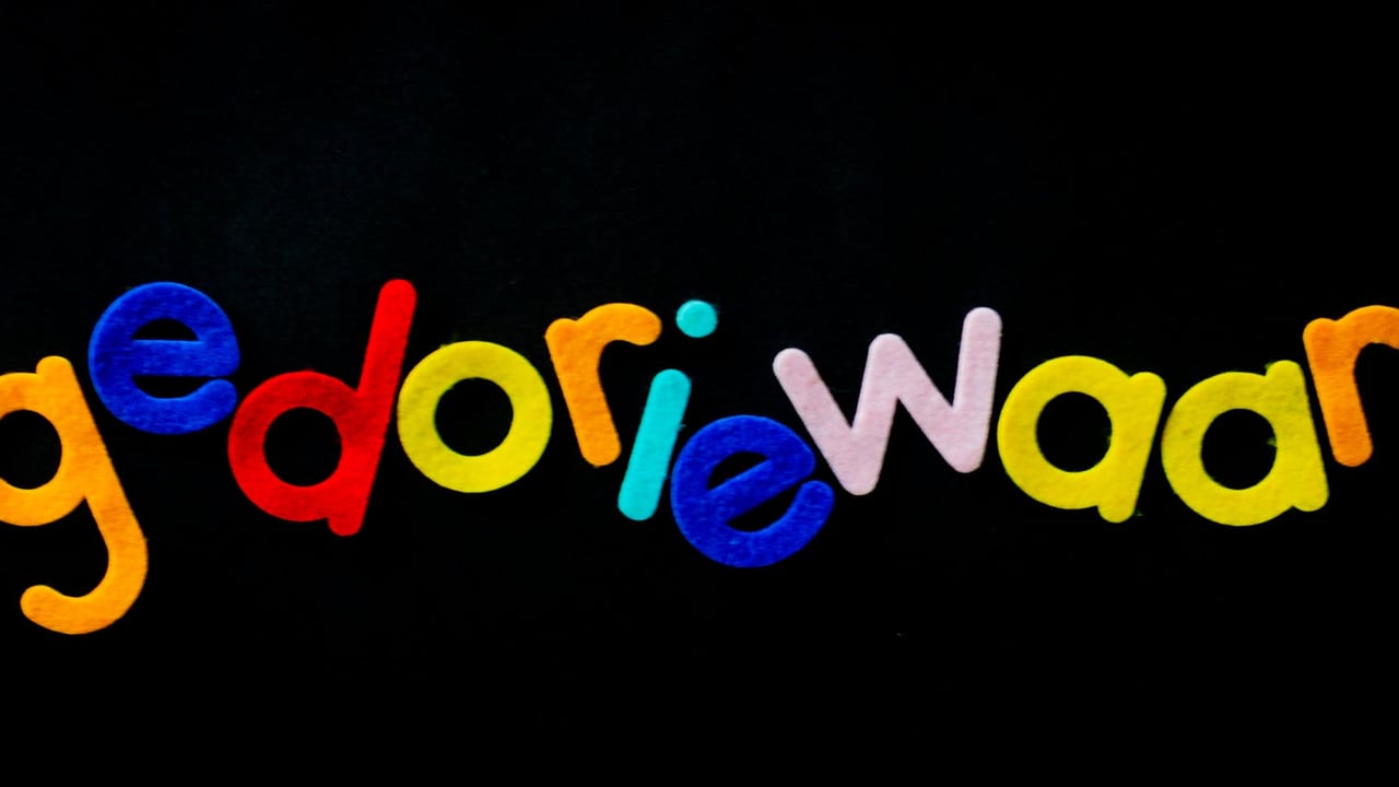 Bright multicolored felt letters spelling a creative word on a black background.