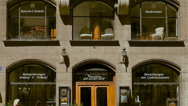 Elegant antique store facade in Munich, showcasing classical furniture and design.