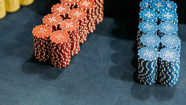 Close-up of neatly stacked red and blue casino chips on a gaming table.