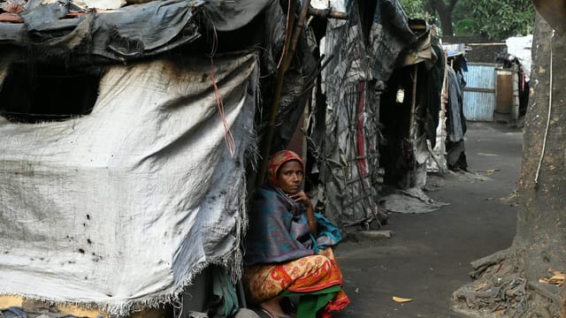 A woman sits outside a temporary shelter in a slum area of Chittagong, Bangladesh.